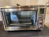 Front view of Hamilton Beach toaster oven showing glass door, interior accessories, and control panel.