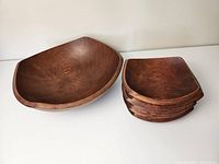 Large wooden salad bowl next to stack of four smaller wooden bowls.