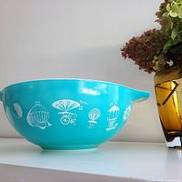 Side view of turquoise Pyrex bowl showing hot air balloon graphics and pouring spout