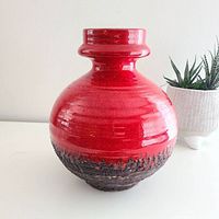 Front and side views of the red lava ceramic vase showing glossy red upper half and textured black lava bottom half with ring neck collar.