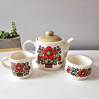 Photo of the full tea set showing the teapot, creamer and sugar bowl with bright floral decoration