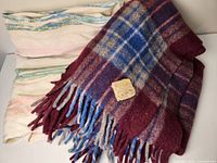 Photo of two folded throws: a plaid wool one and a striped cotton one