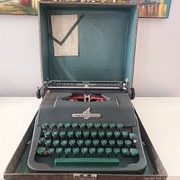 Front view of the green Underwood Universal typewriter with keyboard and logo visible inside carrying case.