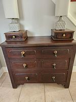 View of vintage three drawer wooden dresser with two small matching wooden drawer boxes on top, showcasing brass pull knobs and wood finish.