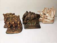 Full view of three pairs of vintage bookends depicting monkeys, horses, and birds.