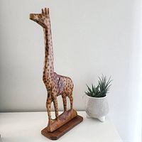 Front view of vintage carved wood giraffe with painted spots and wooden base.