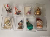Full view of eight vintage Christmas ornaments in individual clear plastic display boxes.