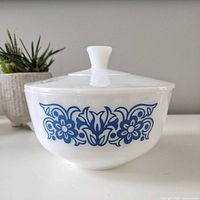 Front side view of vintage Federal casserole refrigerator bowl with blue flower scroll decoration and white lid.