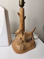 Close-up of wood carved lamp base showing dog figurine and tree-like trunk holder