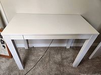 Front view of the white desk showing its simple design and sturdy legs.