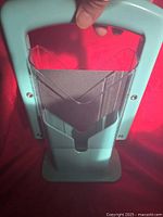 Close-up image of one light blue bagel cutter showing serrated blade and clear red safety guard on top.