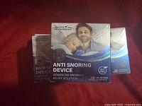 Front view of five SnowShinee Anti Snoring Device boxes showing main product branding and image of sleeping couple