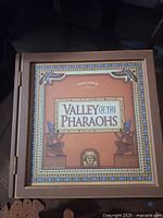 Top view of the closed box showing Valley of the Pharaohs game cover with Egyptian style illustrated border and statues.