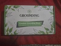 Closed box showing branding and product line - Premium Grounding Sheet, with green leaves design.