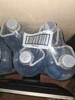 Photo showing 4 large plastic bottles of distilled water wrapped together with barcode label