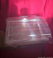 New clear plastic egg tray wrapped in protective plastic on a cardboard box with a red background.