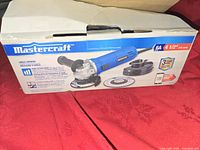 Photo of boxed Mastercraft angle grinder showing product and included accessories with brand, specifications, and warranty info