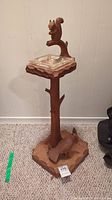 Full view of the wooden standing ashtray showing the tree trunk stand, carved squirrel holding onto the top section surrounding the glass tray.