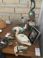 Table setup showing assortment of carved wooden birds including ducks and a framed puffin photo among decorative plates
