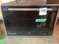 Front view of black and stainless steel countertop oven with glass door, handle and control knob