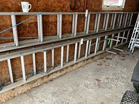 Side view of aluminum extension ladder leaning against particle-board wall