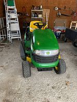 Front view of tractor in garage showing hood, tires, and seat