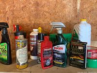 Photo showing various car care liquids on plastic shelf including Bug Tar Remover, Turtle Wax Platinum, Mothers Chrome Polish, and others.