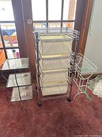 Full view of all three items: metal storage cart, metal and glass stand, and white metal plant stand