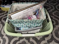 Photo showing medium blue patterned fabric basket with various items inside including dry erase board, pens, and other items
