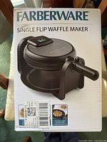 Photo of boxed Faberware single flip waffle maker showing front packaging with brand name, product image, and features.