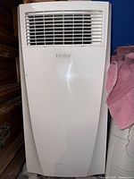 Front view of white Haier portable air conditioner unit showing air vent grille and unit body.