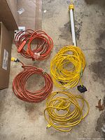 Lot showing multiple heavy duty extension cables coiled on the floor along with a fluorescent shop light tube fixture.
