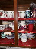 Front view of wooden kitchen cabinet shelves filled with various dishes and containers.