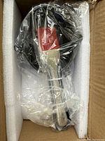 Photo of new Corkys small cast iron sauce pan and silicone brush wrapped in clear plastic inside box.