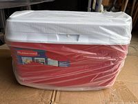 Photo of red and white Rubbermaid cooler wrapped in clear plastic, showing front and top views with brand label