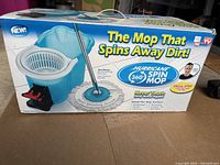Photo showing Hurricane 360 Spin Mop cleaning system box featuring mop, blue bucket with wringer, and product branding and features