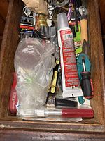 Top drawer filled with various small hand tools including screwdrivers, razors, tube of glue, clamps, and wrenches.