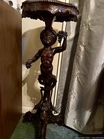 Front view showing cherub support, carved base, and scalloped top