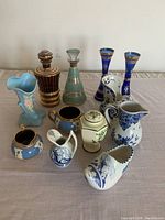 Photo showing all 11 assorted decorative jars, vases, and figurines grouped together on a beige surface.