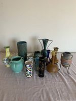 Front view of all 13 vases arranged in 3 rows showing variety in size, shape and color.