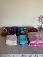 Top-down view of folded assorted bath towels in various colors and patterns on a beige surface.