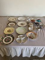 Top view of the lot including all 15 pieces arranged on a table with white lace tablecloth beneath the displayed items.