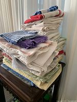 Stack of folded dish towels showing a variety of colors and patterns, including checkered and waffle weave textures.