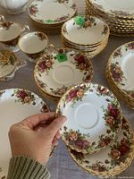 Close-up of saucers and teacups showing rose pattern and gilt rim