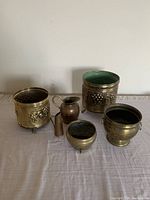 Full view of all five bronze-colored vessels displayed on a white cloth.