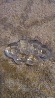 Glass candle holder resting on carpet, photo from a side angle showing five round candle slots arranged in a flower shape.