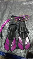 Full set including mask, snorkel, fins, and fishnet carry pouch laid out on a gray surface