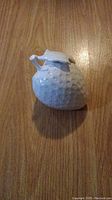 Single white ceramic strawberry-shaped decorative ornament on wooden surface