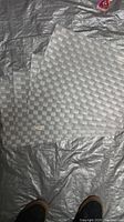 Photo of four light grey woven table mats with a checkered pattern laid on a grey surface.