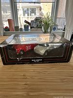 Front view of original black gift box with two die cast Mini Cooper cars visible inside, one red with UK flag and one silver.